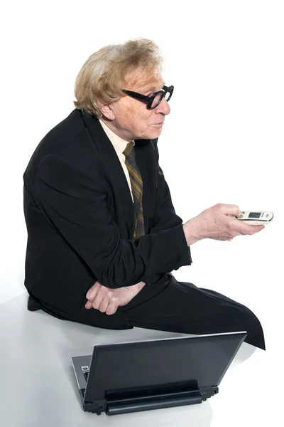 Geschäftsmann sitzt auf einem Tisch neben einem Laptop mit Handy — Stockfoto
