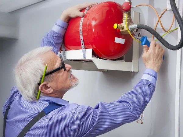 Homem instala extintor de incêndio — Fotografia de Stock