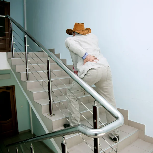 Hombre sube las escaleras con el dolor en la espalda Fotos De Stock