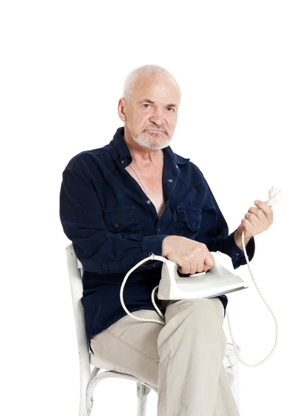 Mann sitzt auf einem Stuhl und hält elektrisches Bügeleisen — Stockfoto