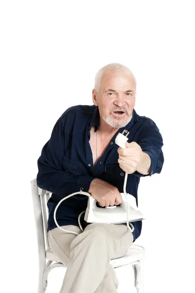 Человек, сидящий на стуле и держащий электрический утюг — стоковое фото