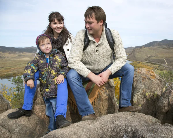 Família feliz sentada na pedra — Fotografia de Stock