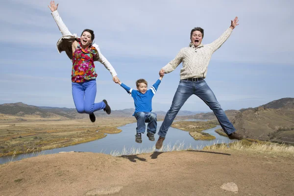 Springen op de berg en gelukkige familie — Stockfoto