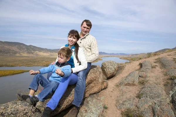 Happy family sitting on the stone — Stock Photo, Image