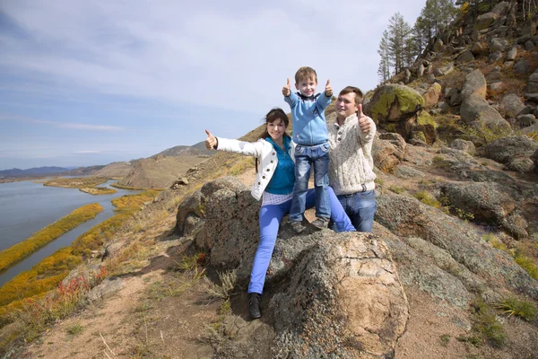 Mutlu aile taş üzerine oturan ve başparmak gösterilen — Stok fotoğraf