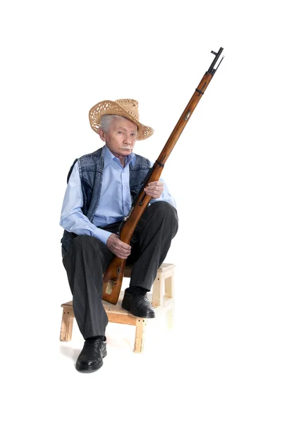 Un hombre con un sombrero sentado con un arma — Foto de Stock