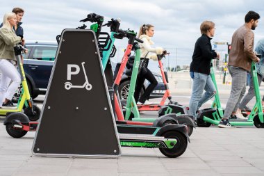 Stockholm, İsveç - 21 Ağustos 2021: Trafiğin yoğun olduğu saatlerde insanlar sokakta elektrikli scooterlarla seyahat ediyor. Kaldırımda elektrikli scooterlar bir e-scooterın park alanında park halinde.. 