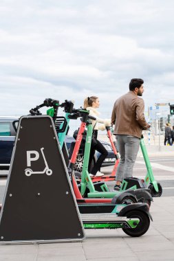 Stockholm, İsveç - 21 Ağustos 2021: E-scooterların park alanında park etmiş farklı şirketlerin elektrikli scooterları. Sokakta, mobiletlerle seyahat eden insanlar - popüler bir ulaşım aracı..