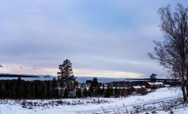 Gün batımında dağlarda kış manzarası. Siljan Gölü ve ufukta dağlarla birlikte Dalarna 'daki cennet manzarası. Fotoğraf İsveç 'in Tllberg köyünde çekildi..