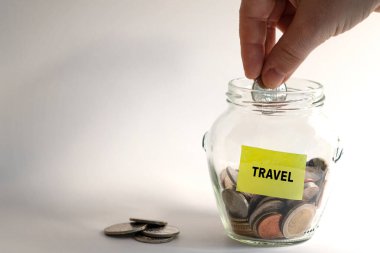 Tatil için para biriktirme ya da yurtdışına seyahat edebilme kavramı. Hem cam kavanoza hem de bir yolculuk için haritada bulunan bozuk paralar. Fotoğraf: 17 Ocak 2022 Stockholm, İsveç 