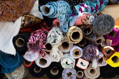 Kumaş rulo ya da kumaş cıvatalar farklı desenler ve renklerde. Tekstil ve kumaş açık pazarda satılıyor. Fotoğraf Notting Hill, Londra 'daki Portobello yol pazarında çekildi..