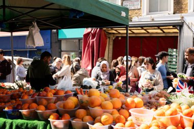London, United Kingdom - April 30 2022: People buying fruits and vegetables at market stand at the Portobello road market in Notting Hill, London on the weekend. 
