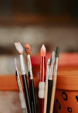 Resim yapmak için boya fırçası seti. Arka planda çanak çömlek ve terra cotta kapları var.. 