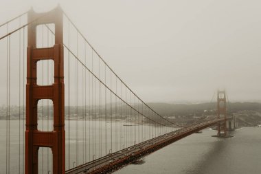 View of landmark golden gate bridge from scenic viewpoint with the city in the background. Morning with fog and overcast weather. Photo taken in San Francisco, California, USA