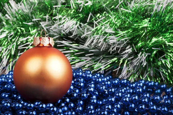 Orange Christmas ball and blue beads on a background of green ga — Stock Photo, Image