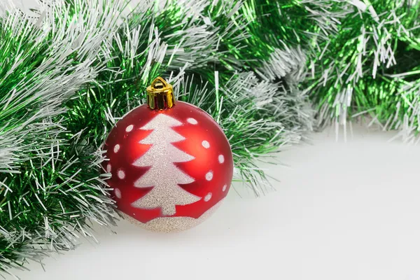 Red Christmas ball with painted Christmas tree and green garland — Stock Photo, Image