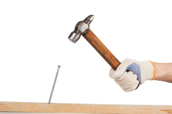 Männliche Hand im Arbeitshandschuh schlägt Nagel in Holzbrett — Stockfoto