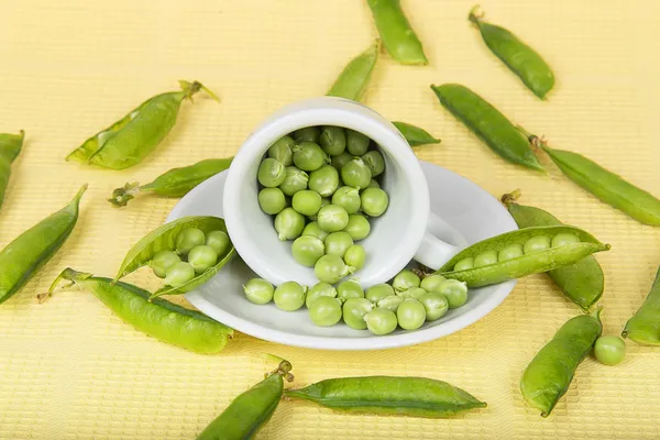 Fresh green peas in an inverted white cup — Stock Photo, Image