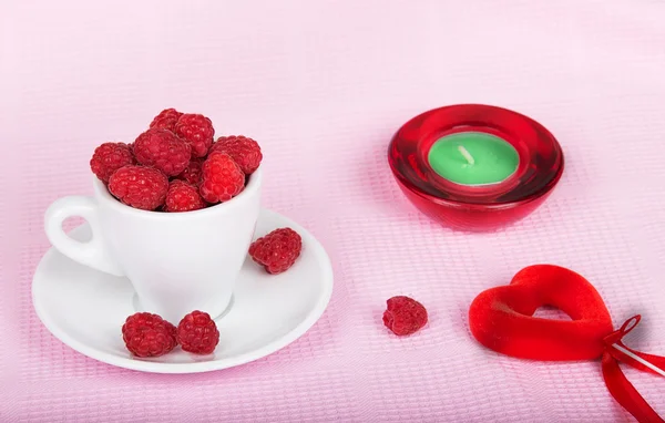 Framboises dans une tasse, une bougie et un cœur — Photo