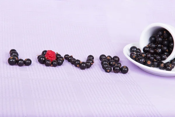 Inverted white cup with black currants with an inscription "love — Stock Photo, Image
