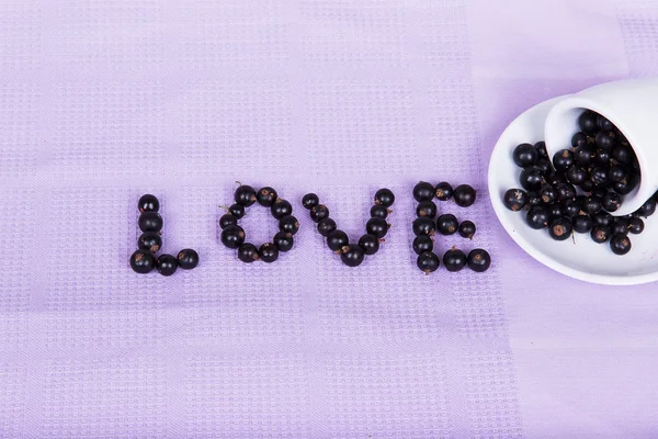 Inverted white cup with black currants with an inscription "love — Stock Photo, Image