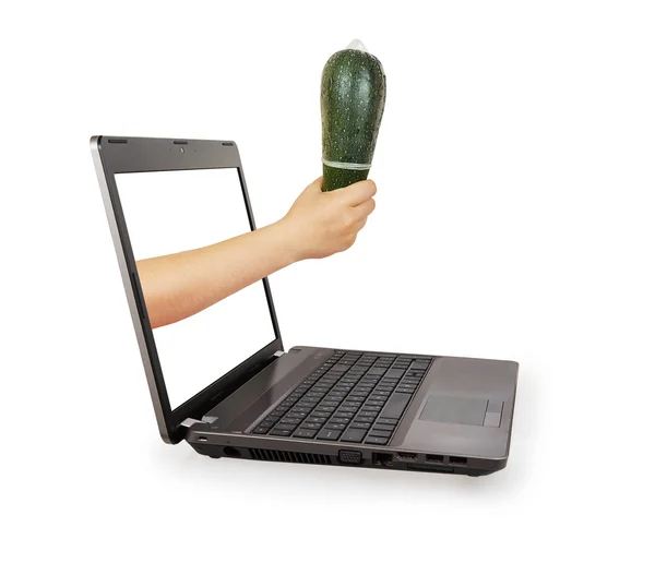 Woman's hand holding green zucchini with a condom from a laptop — Stock Photo, Image