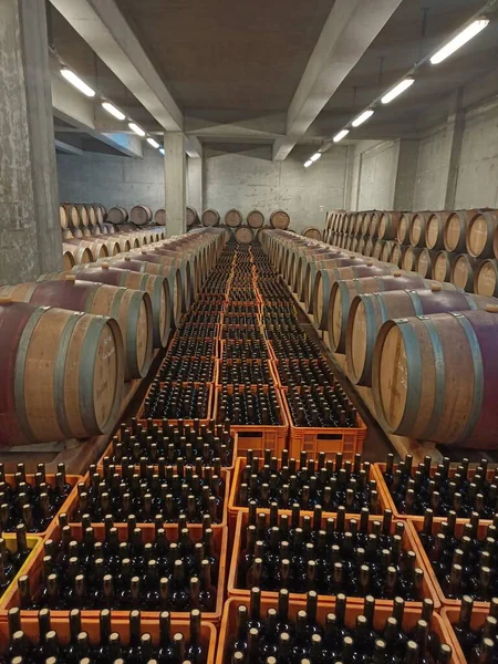 Many barrels in a wine cellar. Wine bottles and crates with bottles. Antique look.