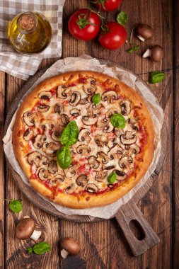 Mantarlı pizza. Amerikan usulü ev yapımı mantarlı pizza, mozzarella peyniri ve domates sosu. Taze yemlenmiş ve fesleğen yapraklarıyla servis edilmiş..