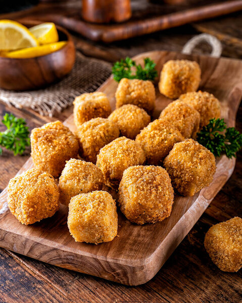 Delicious breaded fish nugget snacks on a rustic wood table top.