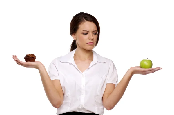 Business woman choosing between cake and fruit — Stock Photo, Image