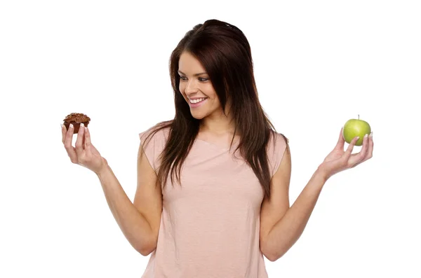 Brunett kvinna håller upp ett äpple och tårta — Stockfoto