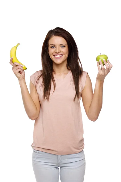 Brunette woman holding up an apple and banana — Stock Photo, Image