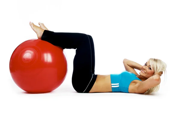Mujer rubia joven haciendo ejercicio en una pelota de fitness roja —  Fotos de Stock