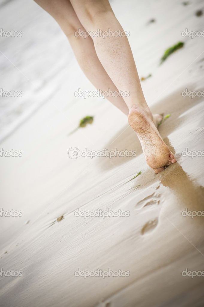 Woman's legs walking along the beach