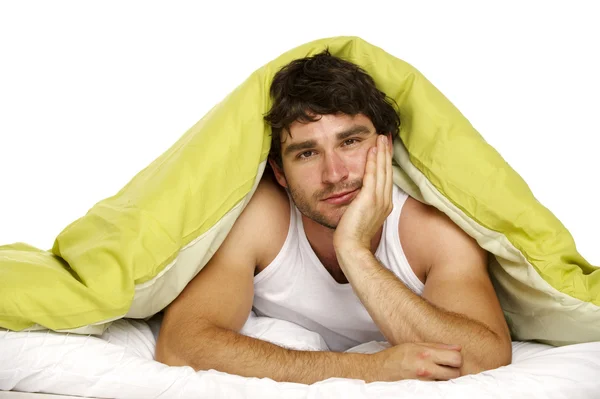 Man in bed under a green duvet — Stock Photo, Image