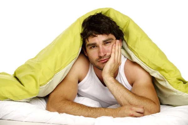 Man tired in bed under a green duvet — Stock Photo, Image