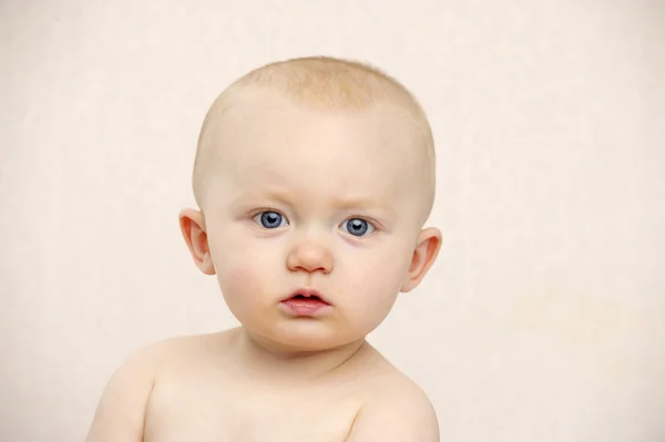 Baby blickt in die Kamera auf einem Pfirsichhintergrund — Stockfoto