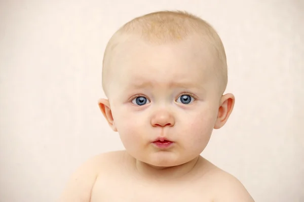 Baby kijken naar de camera op een perzik achtergrond — Stockfoto