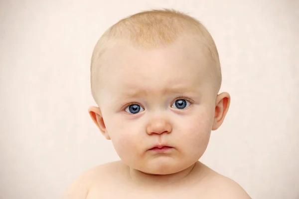 Baby kijken naar de camera op een perzik achtergrond — Stockfoto