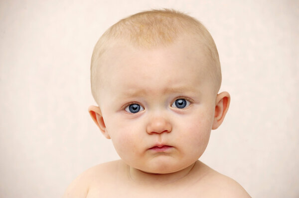 Baby looking at the camera on a peach background