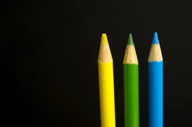 Sarı, yeşil ve mavi renkli boya kalemi siyah backgr üzerinde kalem