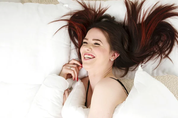 Donna a letto ridendo Immagine Stock