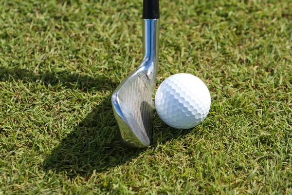 Golf ball and club in grass — Stock Photo, Image