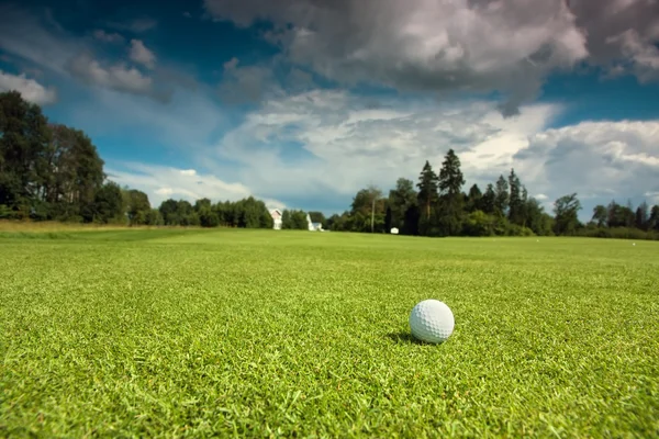 Μπάλα του γκολφ για το γκολφ, πράσινο γρασίδι, μπλε ουρανό και άσπρα σύννεφα — Φωτογραφία Αρχείου
