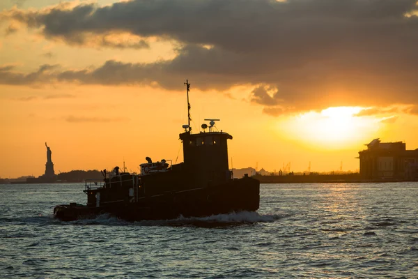 Tugboat heads towards New York from Liberty Island at sunset — Stock Photo, Image