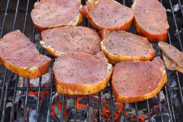 Thick seasoned pork chops cooking on the grill — Stock Photo, Image