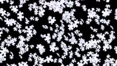 Birçok beyaz yapboz parçası siyah arka planda havada yüzüyor. İş başarısı ve çözüm konsepti. 3B döngü canlandırması.