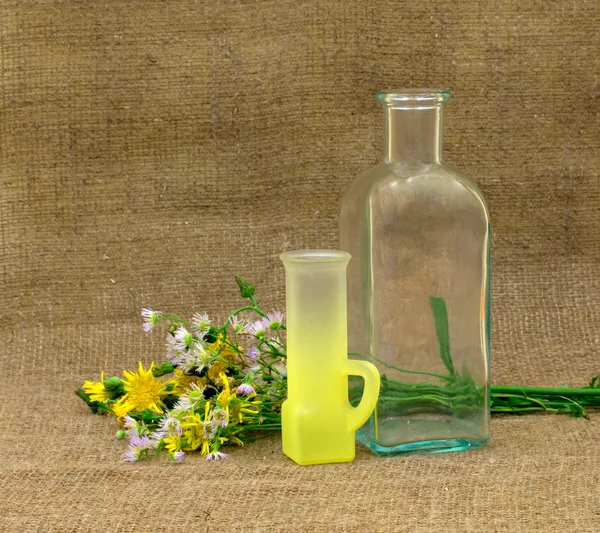 Natureza morta com garrafa vazia, vidro e flores — Fotografia de Stock