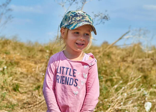 Petite fille porter casquette militaire hipster à l'extérieur regardant loin dans la prairie — Photo