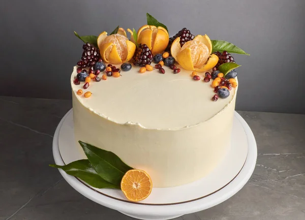 Sabroso pastel blanco decorado con naranjas de granada fondo gris arándano — Foto de Stock